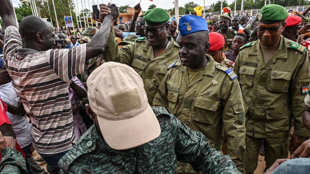 Des militaires marchent parmi une foule en liesse.