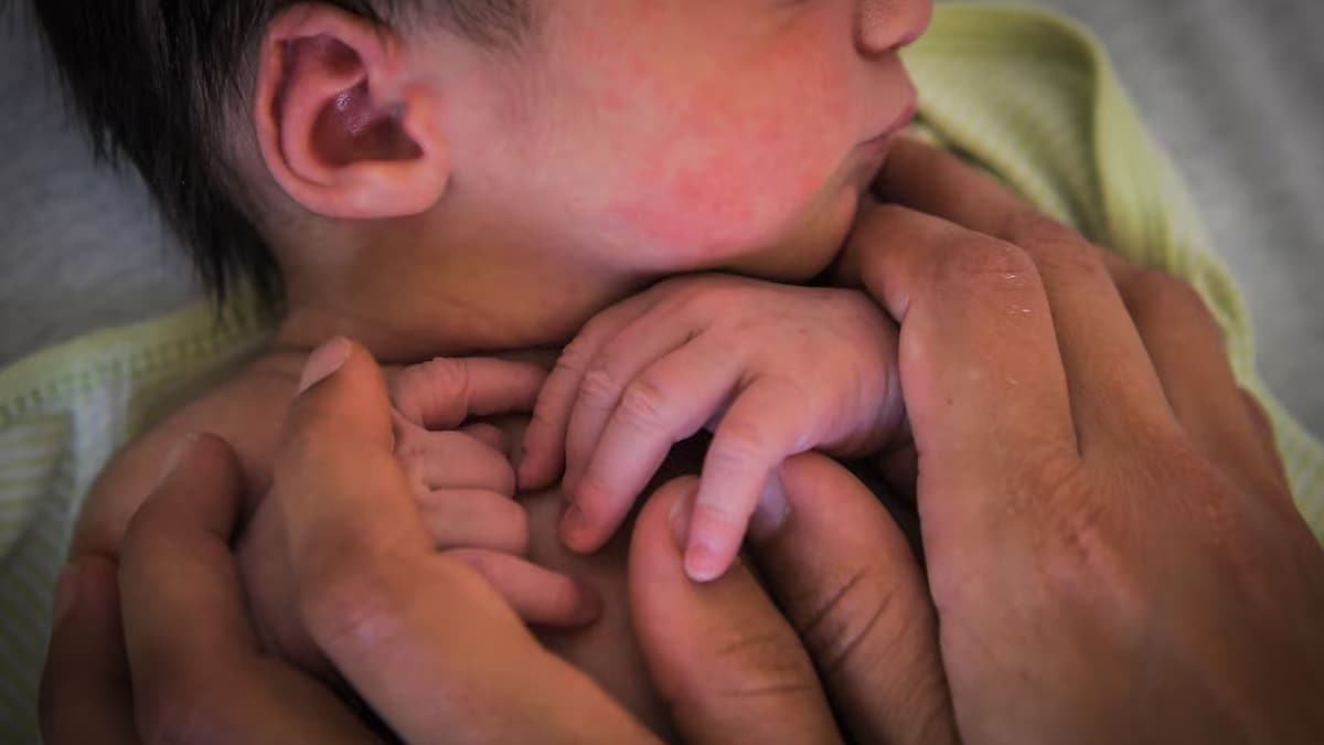 Deux mains d'adulte tiennent un nouveau-né.
