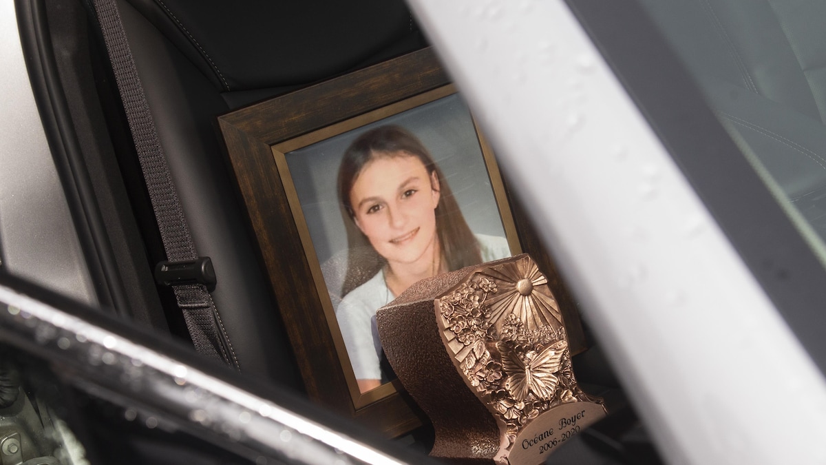 Une photo encadrée d'Océane Boyer est posée sur le banc passager d'une voiture.