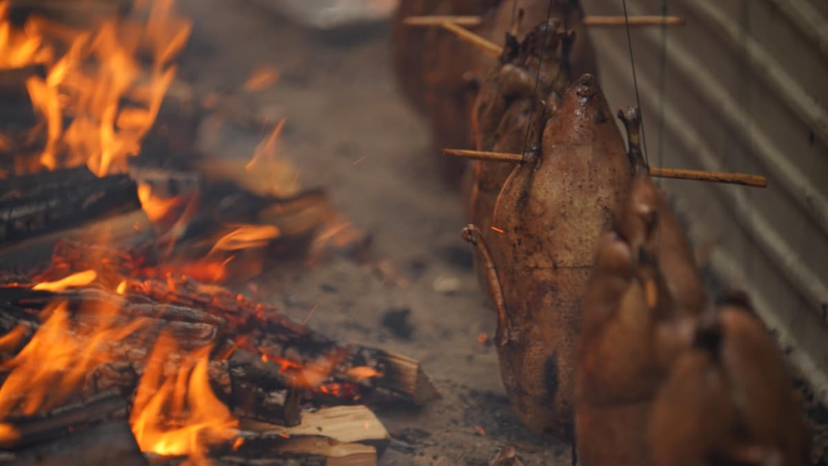 Des oies qui cuisent près d'un feu.