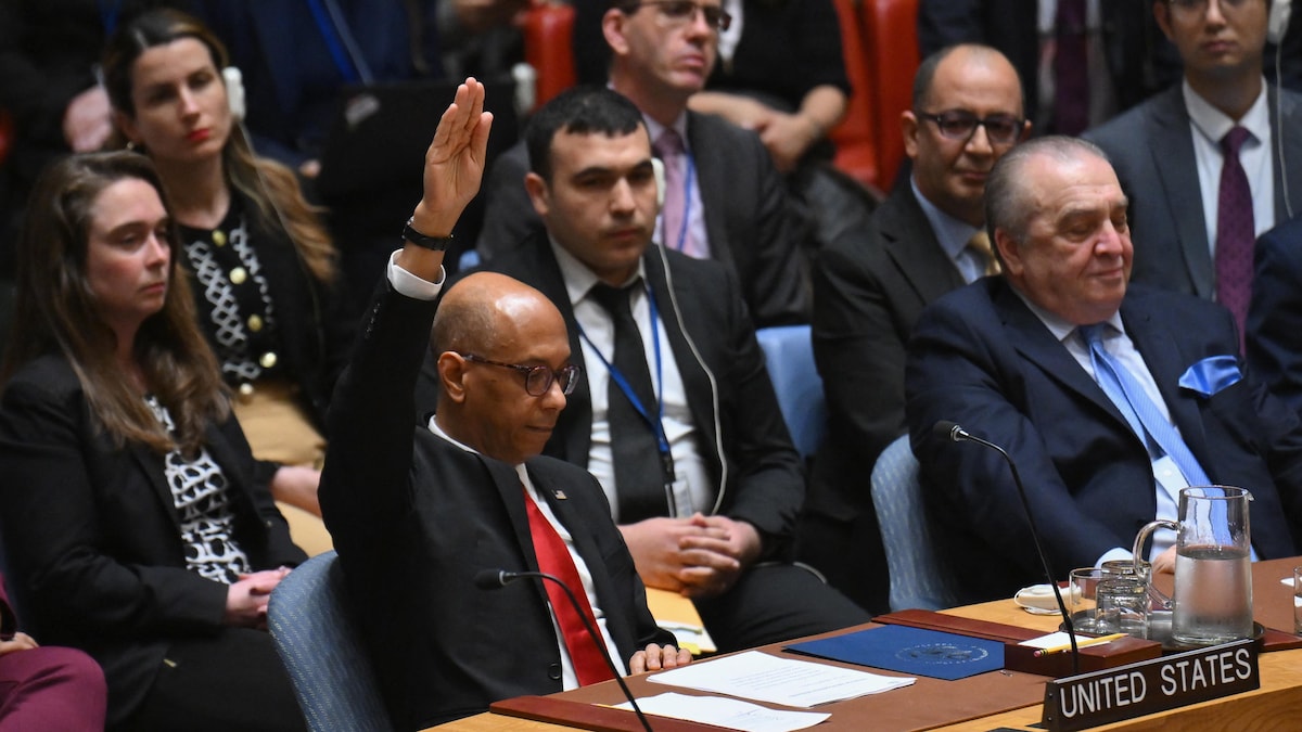 Un homme lève la main droite pendant une réunion.
