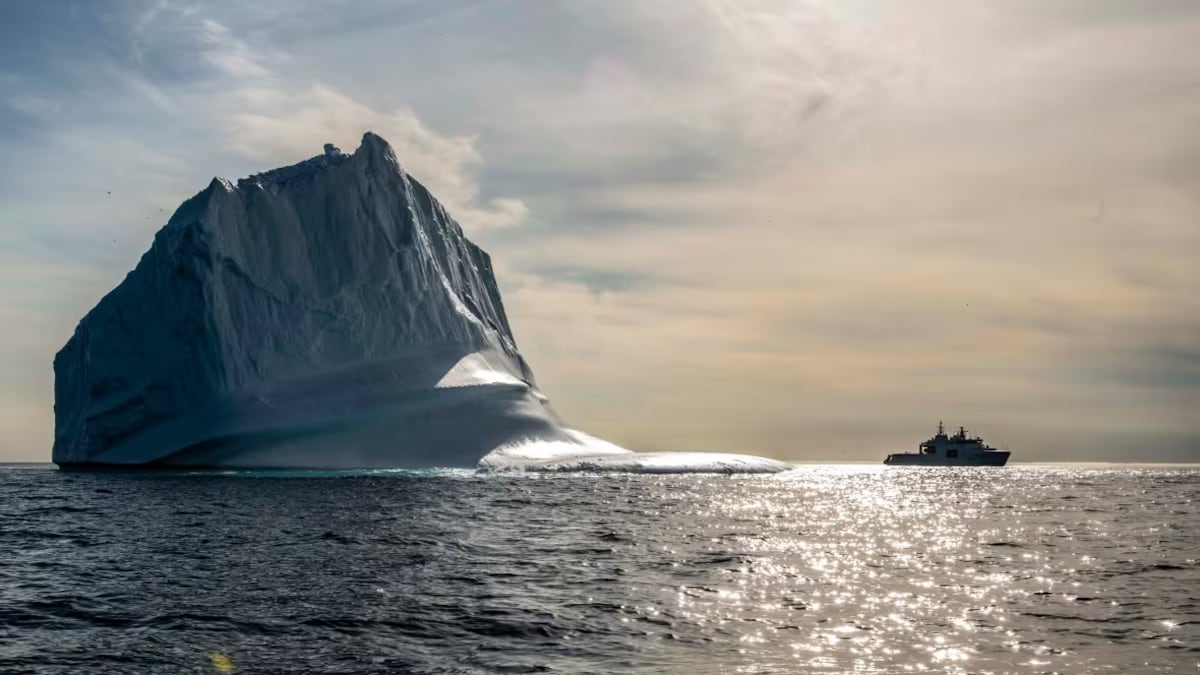Le navire est tout petit à côté de l'iceberg. 