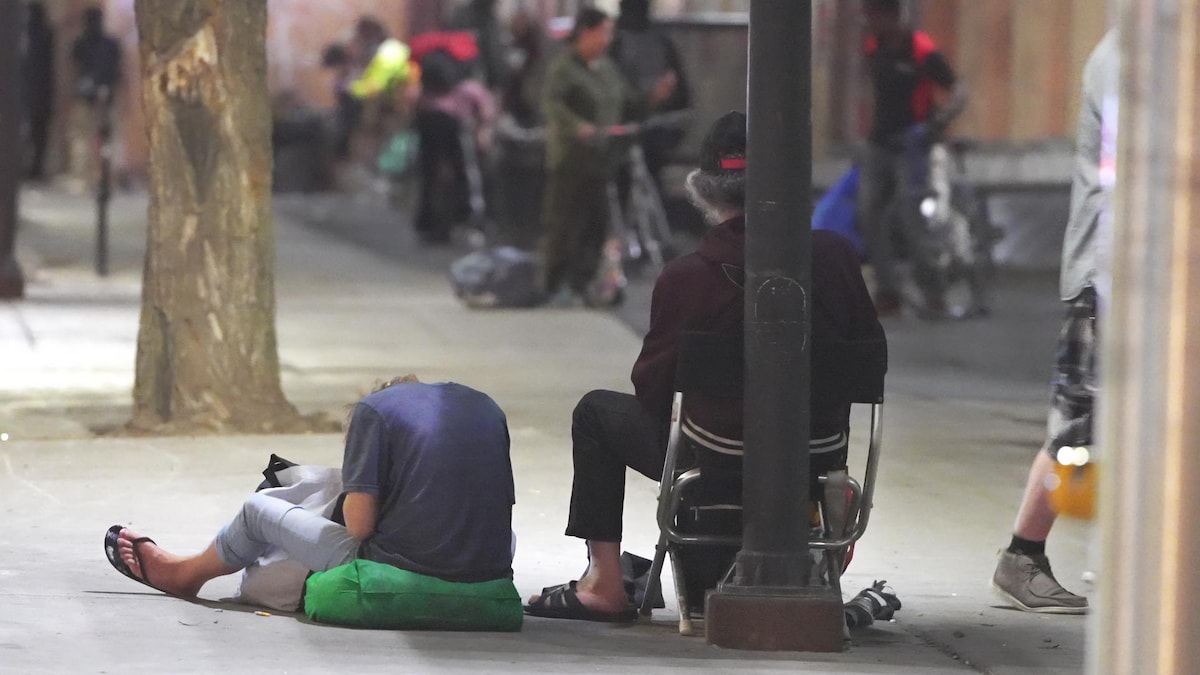 Deux hommes assis sur un trottoir.