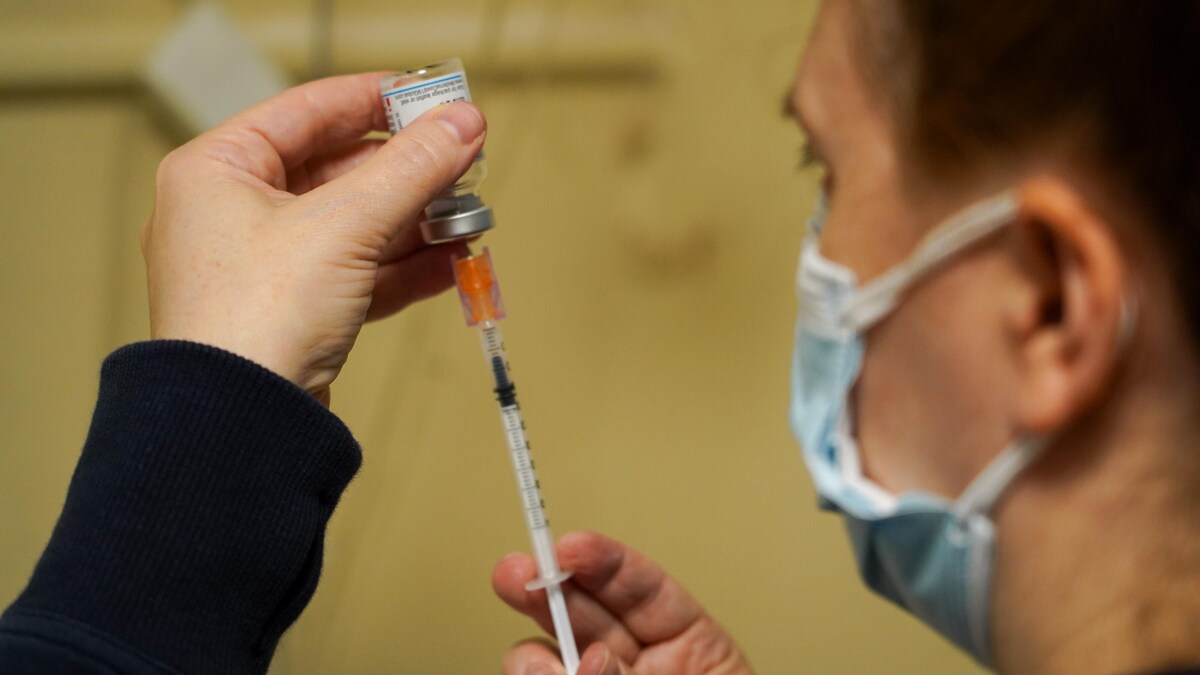 Un homme à un centre de vaccination à Ottawa remplit une seringue.