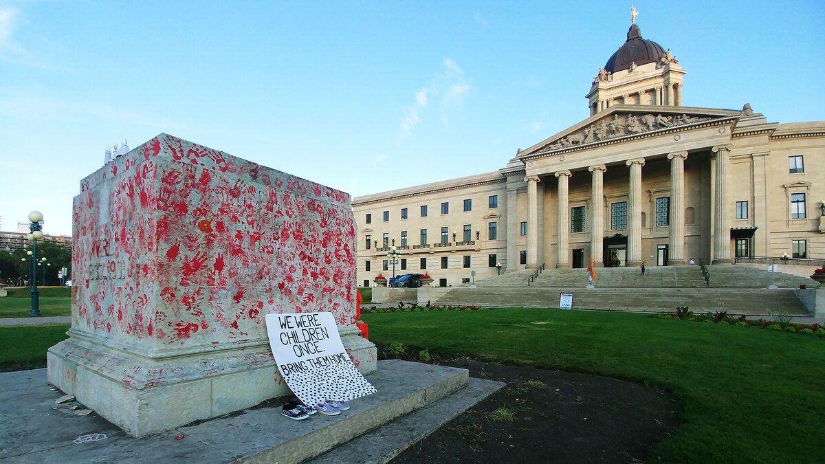 Le socle sur lequel se trouvait la statue de la reine Victoria devant le palais législatif du Manitoba, à Winnipeg, est vide et des mains rouges apparaissent dessus.