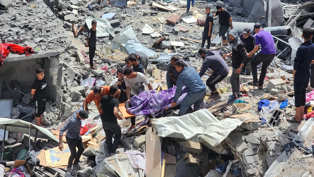 Des Palestiniens, marchant dans des débris d'une maison détruite, portent le corps d'une personne tuée.
