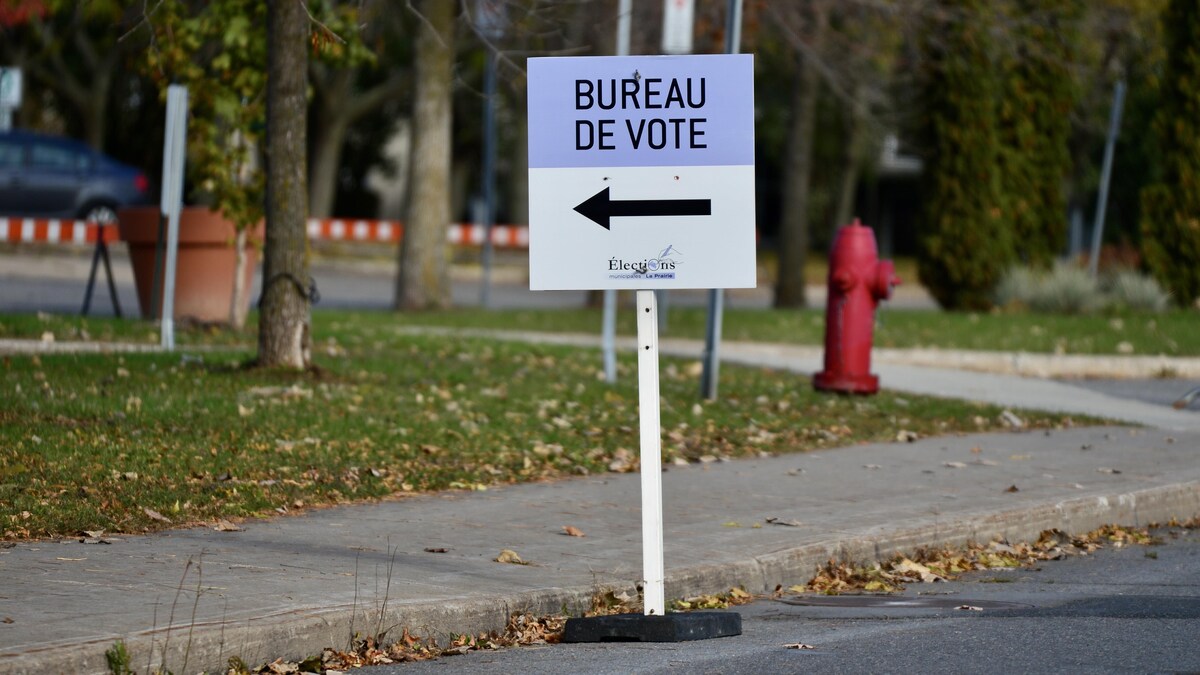 Une pancarte annonçant un bureau de vote, avec une borne-fontaine en arrière-plan.