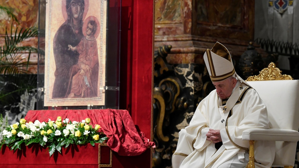 Le pape François assis sur un fauteuil. la tête inclinée et les mains croisées.