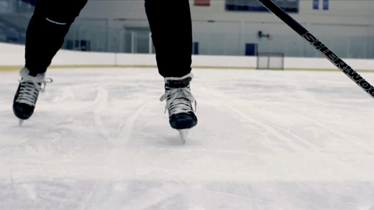 Gros plan sur deux pieds chaussés de patins glissants sur une patinoire intérieure.