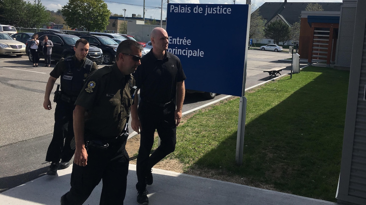 Accompagné de deux policiers, Patrick Chénard arrive au palais de justice Rimouski.