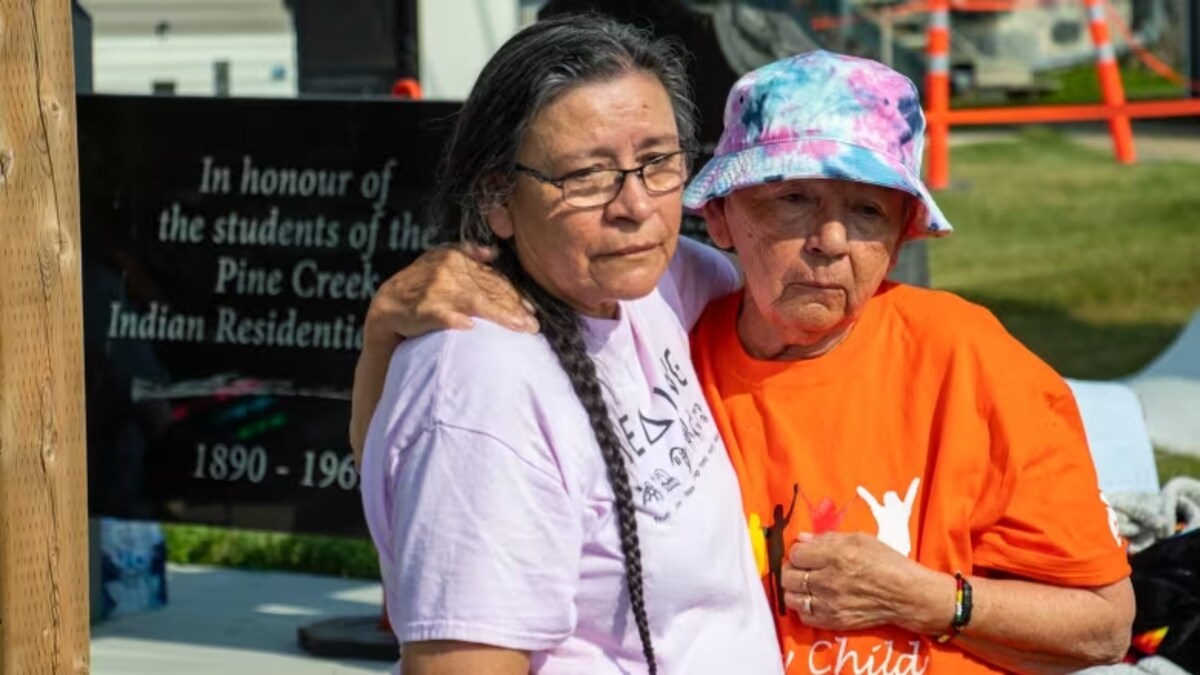 Brenda Catcheway et sa mère Evelyn Lariviere écoutent les enfants jouer aux tambours à Minegoziibe Anishinabe pour la recherche de sépultures non marquées. 