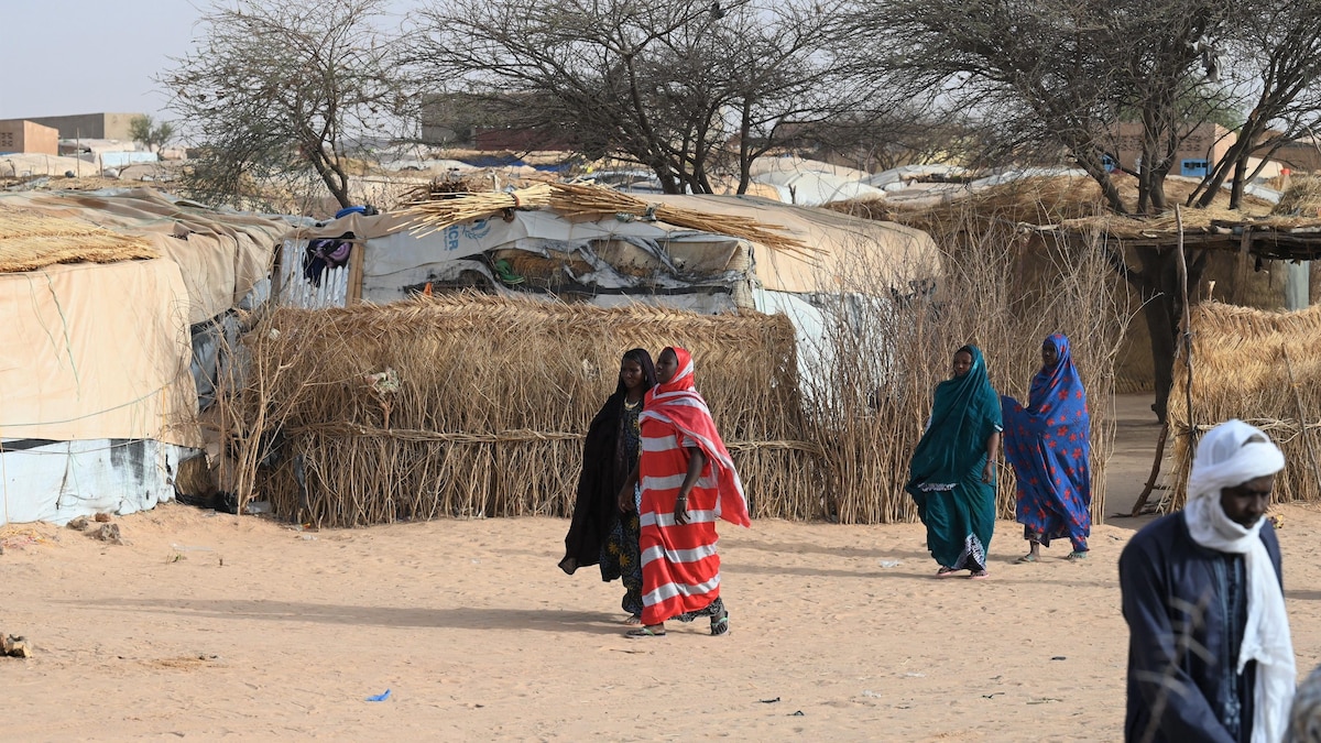 Des personnes marchent dans un camp de déplacés internes sur un sol aride.