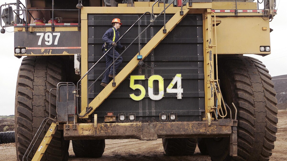 Un travailleur de Syncrude monte sur un immense camion, près de Fort McMurray, en 2006.