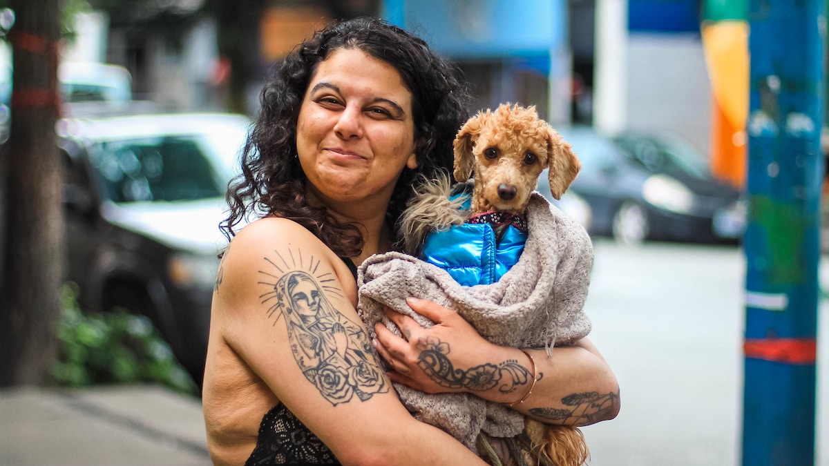 Portrait de Nina Aldewood avec son chien dans les bras dans le quartier de Downtown Eastside de Vancouver en juin 2022. 

