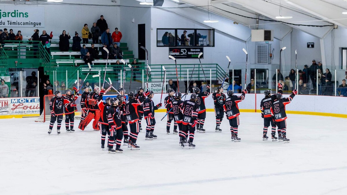 Les joueurs d'une équipe de hockey, le bâton dans les airs, saluent leurs partisans après un match.