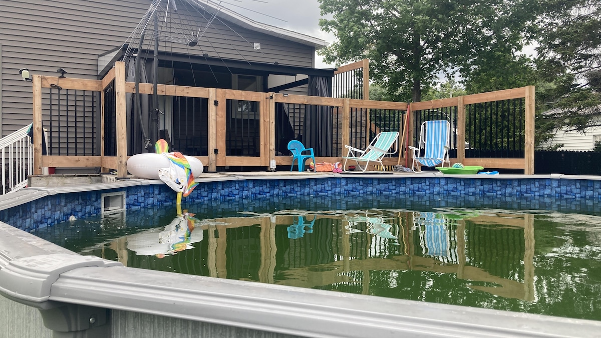 Une piscine dont l'eau est verte. Des jouets se trouvent sur le balcon.