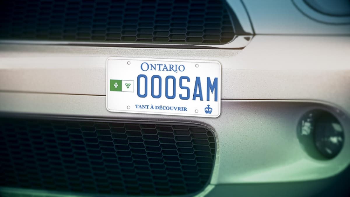 Une plaque d'immatriculation de l'Ontario avec le drapeau franco-ontarien, sur le devant d'une voiture.