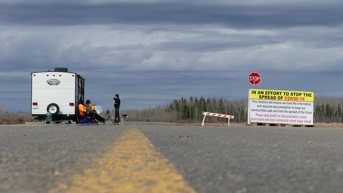 Des gens, assis, attendent que les voitures passent pour interroger les conducteurs.