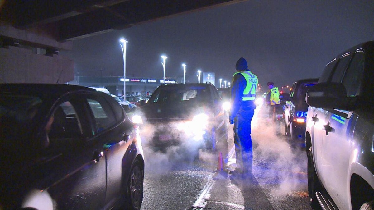 Deux policers, le soir, entre deux files de voiture. 