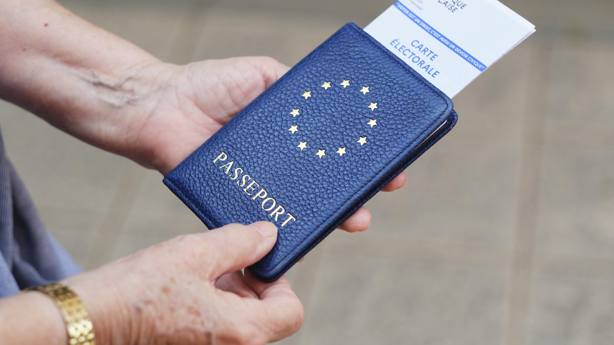 Un homme tient dans ses mains un passeport et une carte électorale.