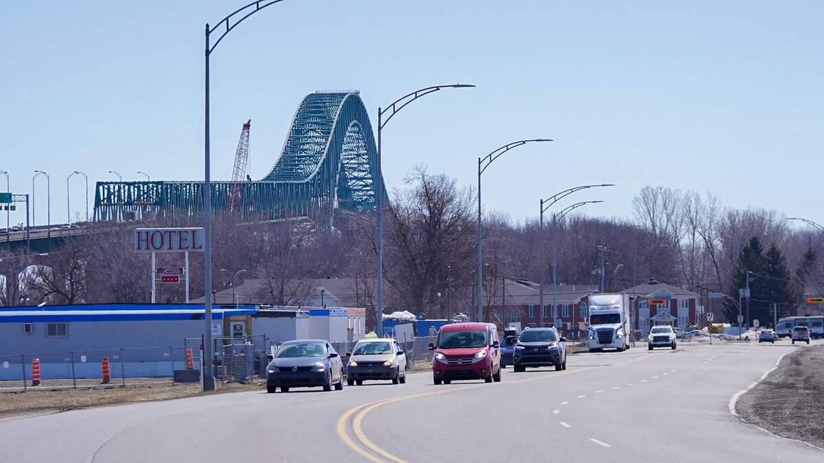 Le pont Laviolette derrière une affiche d'hôtel et une rue avec des voitures.