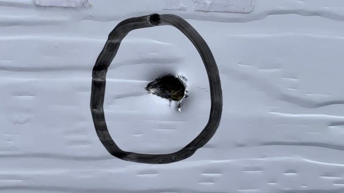 Une marque de balle dans un mur extérieur est entourée par un cercle tracé au marqueur noir.
