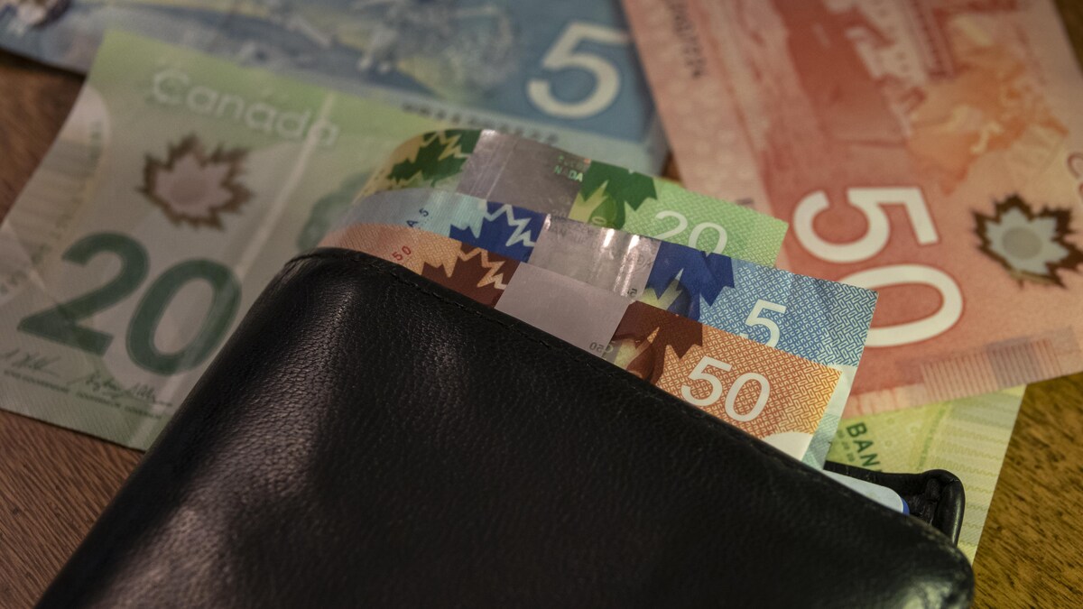 Des billets de 5 $, 20 $ et 50 $ dans un portefeuille sur une table.