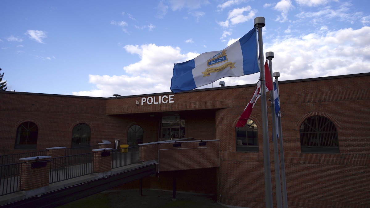 Façade du poste de police de Trois-Rivières avec des drapeaux qui flottent sur des mâts.