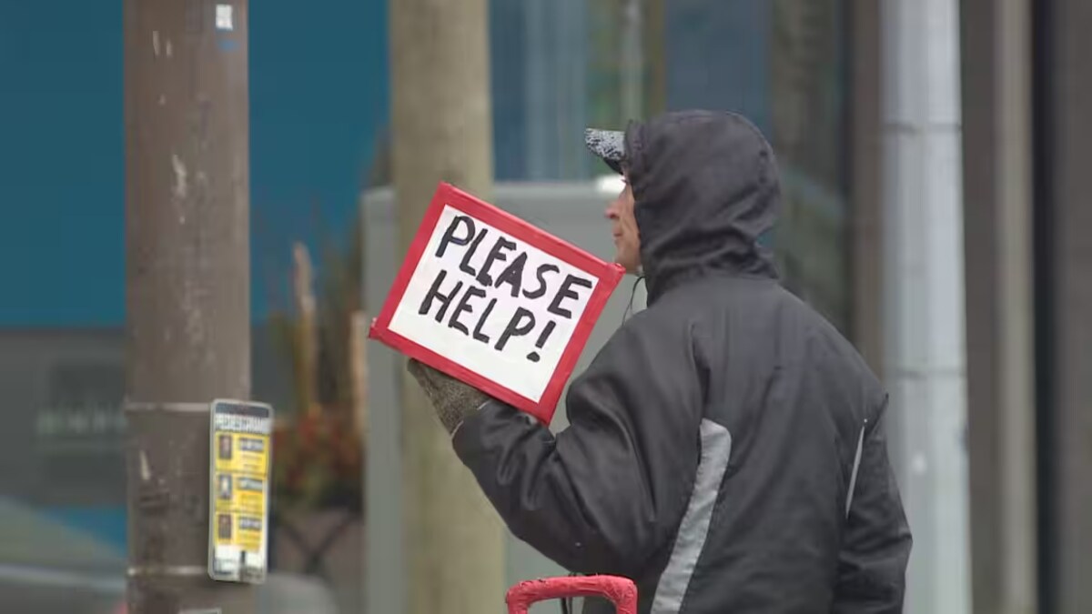 Un homme dehors avec une pancarte, demandant de l'aide.