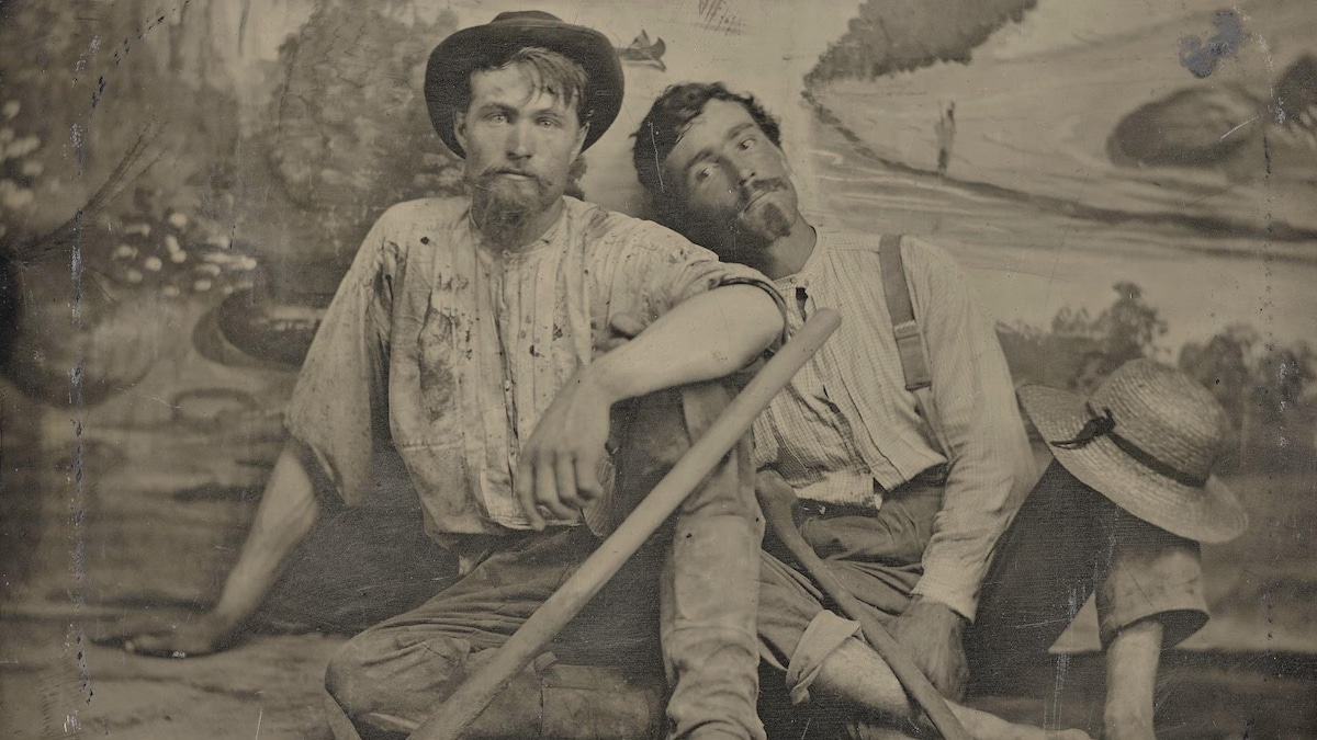 C'est une photo ancienne montrant les deux hommes assis par terre, dans leurs vêtements de prospecteurs, devant une tapisserie de studio de photo. Ils ont l'air sales et plutôt fatigués. 