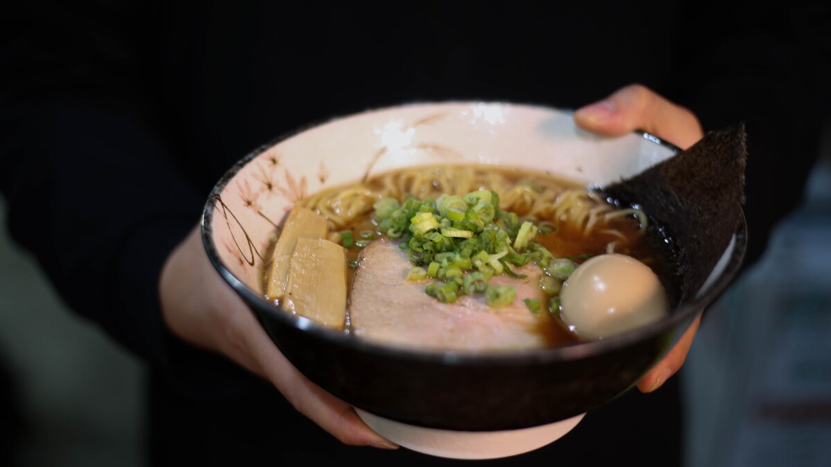 Des mains tiennent un bol de ramen.