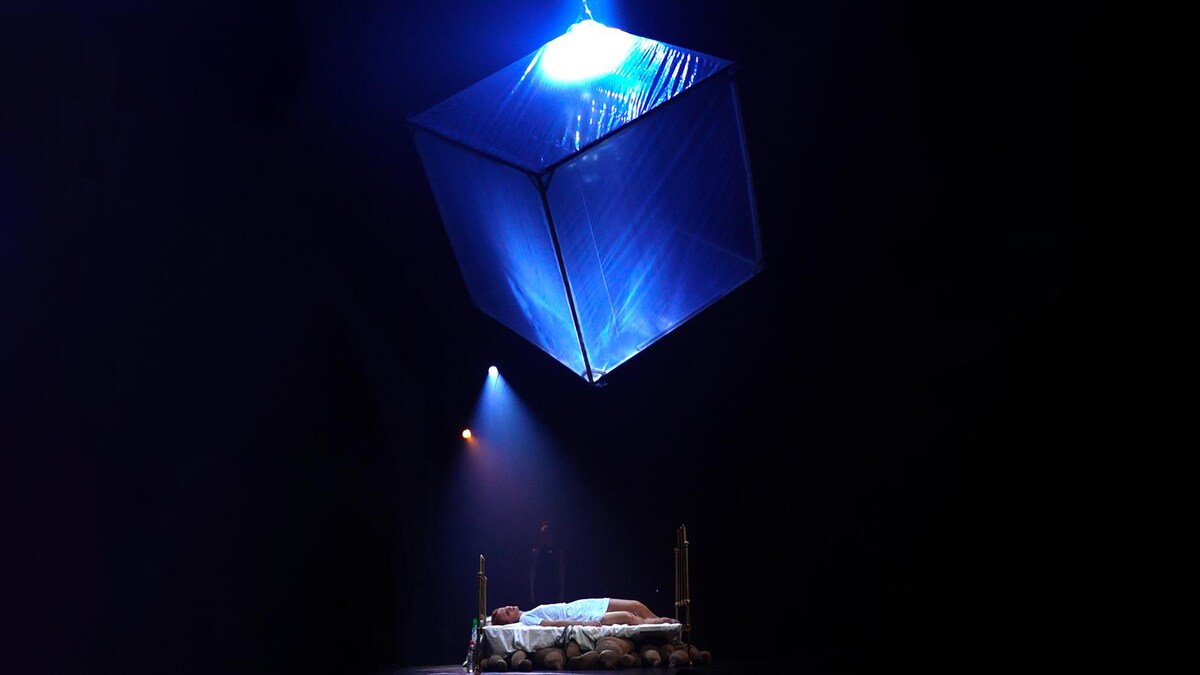 Une personne est allongée sur un lit avec un grand cube transparent au-dessus d'elle.