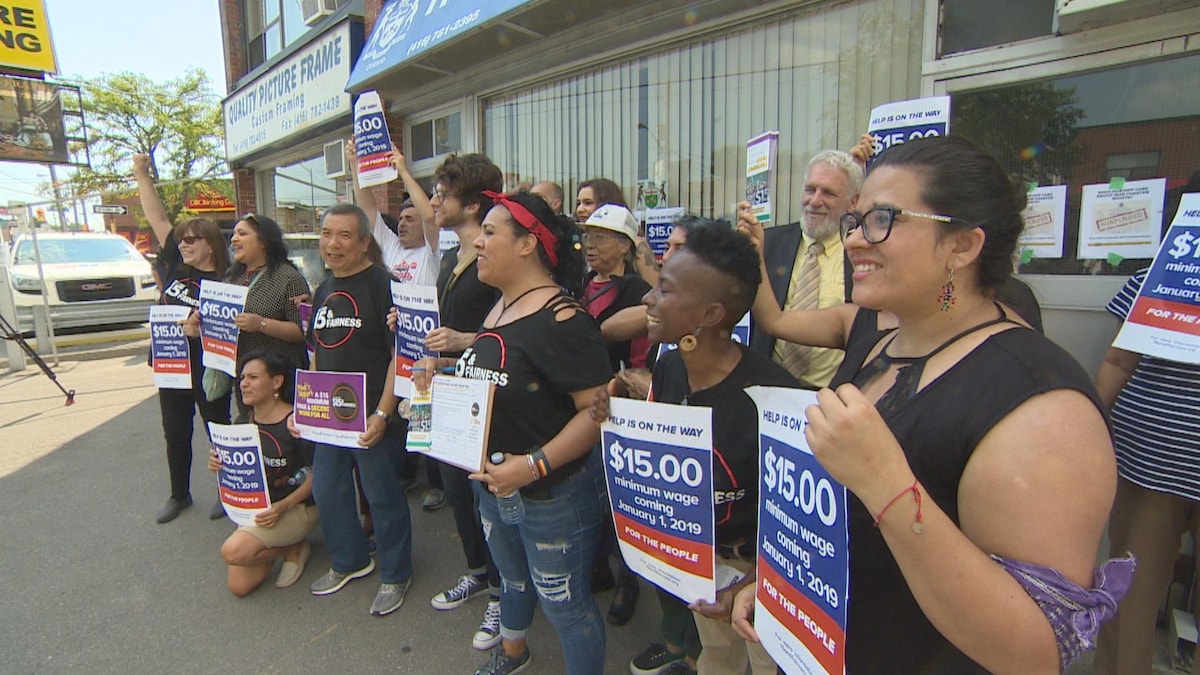 Des militants en faveur de l'augmentation du salaire minimum à 15 $ l'heure sont rassemblés dans la circonscription provinciale d'Eglinton-Lawrence, à Toronto. 