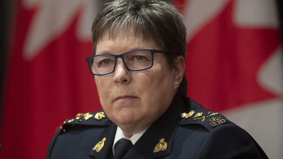 Brenda Lucki en uniforme devant un drapeau canadien.