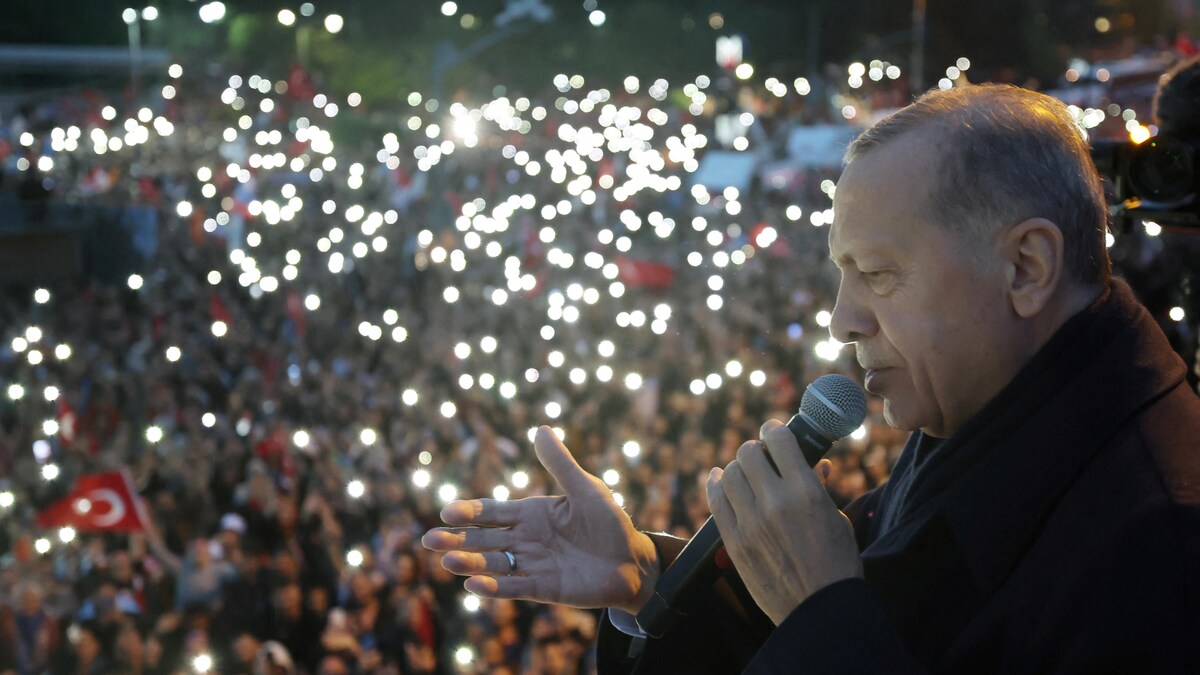Recep Tayyip Erdogan, de profil, fait un discours avec un micro devant une foule. 