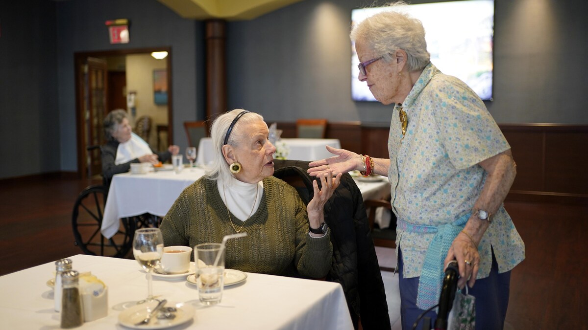 Deux dames âgées discutent dans la salle à manger d'une maison de retraite.