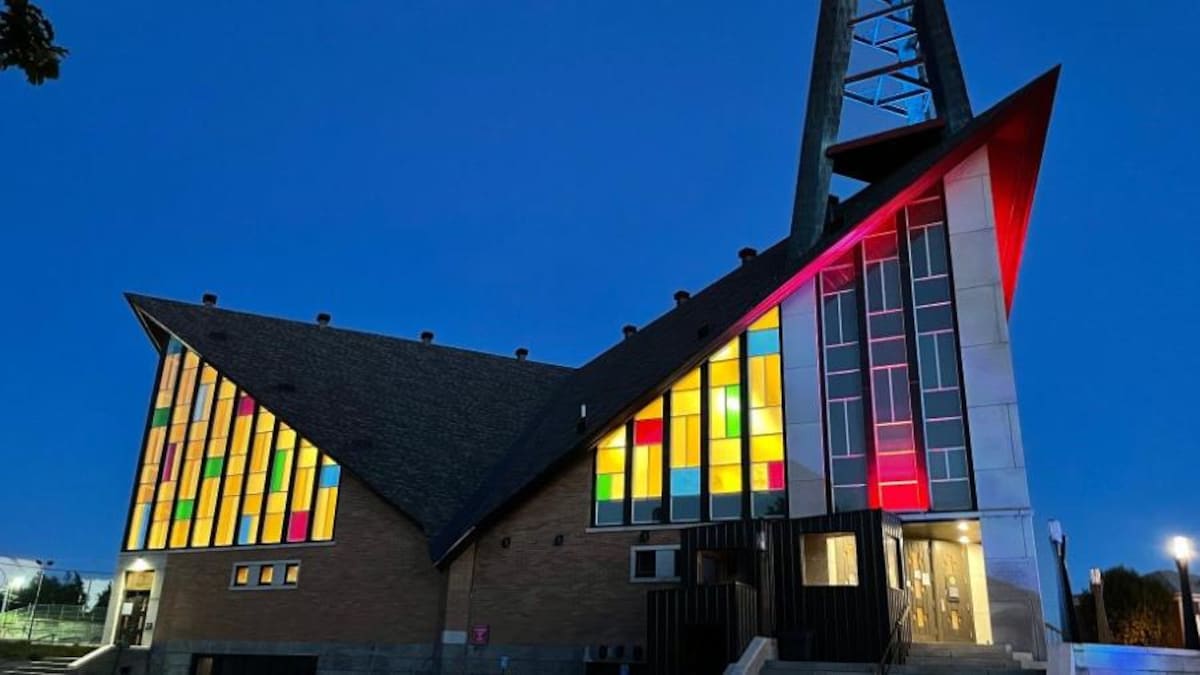 L'église Saint-Yves à Rimouski-Est illuminée de l'intérieur, les vitraux géométriques scintillants, en soirée.