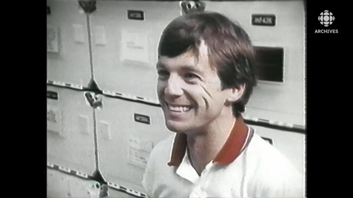 Robert Thirsk tout sourire, assis dans un simulateur de navette.