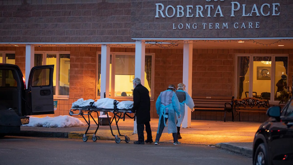 Un homme pousse une civière devant un centre de soins de longue durée.