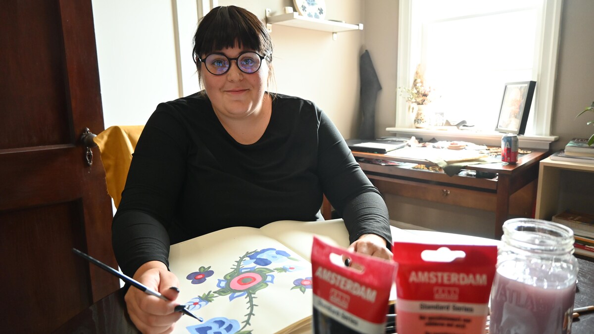 L'artiste Robyn Adams pinceau a la main est assise a son bureau 