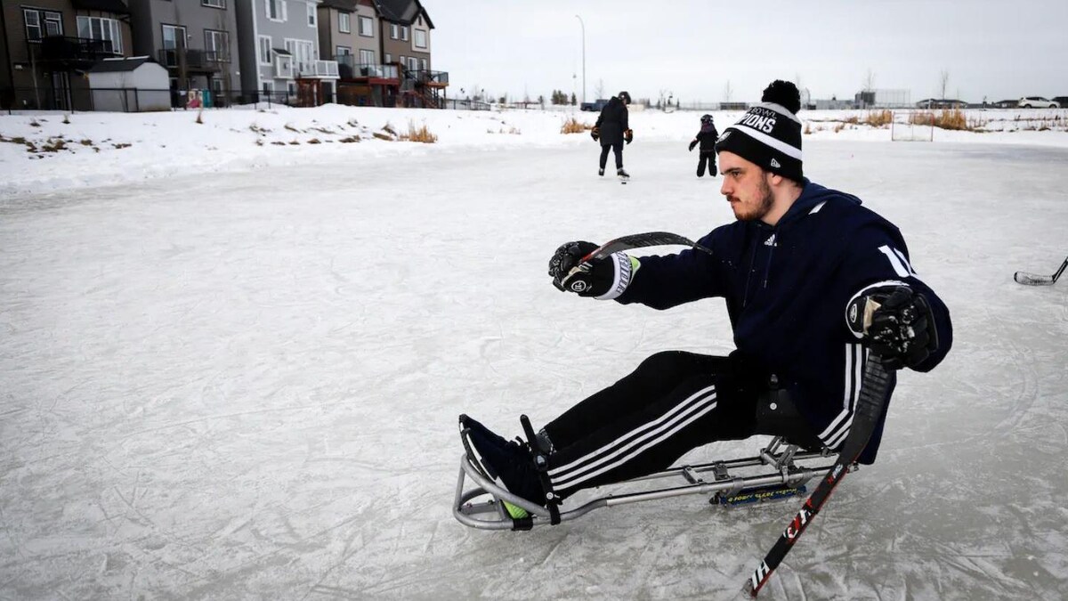 Ryan Straschnitzki jouant au hockey sur sa luge, derrière la maison familiale.