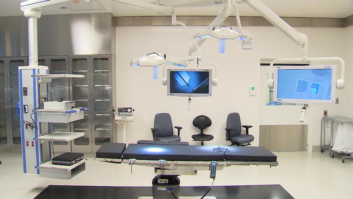 Une salle d'opération où l'on peut voir une table, des supports à instruments chirurgicaux et des écrans, notamment.