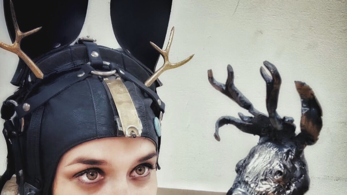 Une personne avec une installation sur la tête, à côté d'une sculpture en métal.