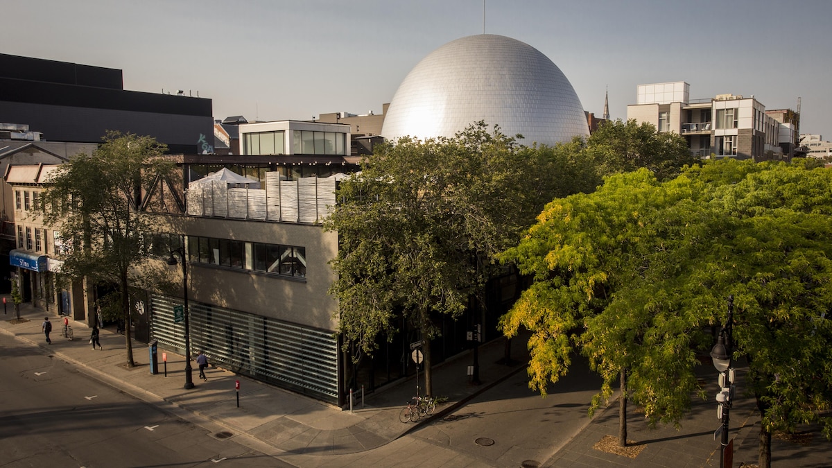 L'édifice de la SAT, sur le boulevard Saint-Laurent, à Montréal. Le dôme de la satosphère est visible au-dessus des arbres.