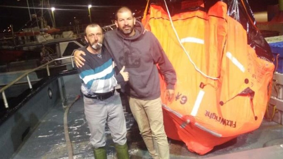 Deux hommes au port de Grande-Rivière, devant un canot de sauvetage.