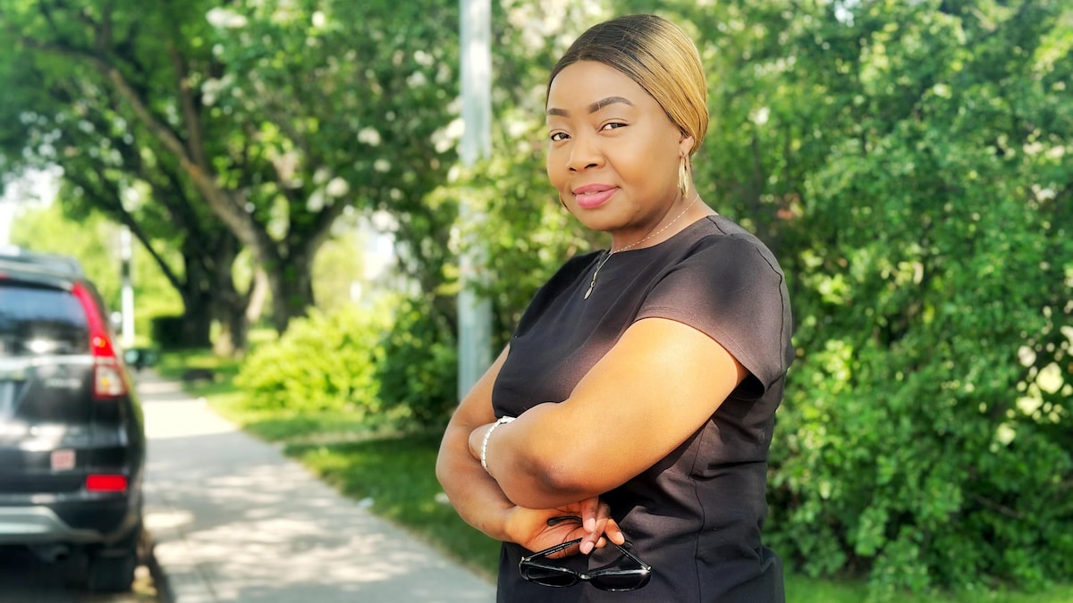 Serge Makuetche debout dehors dans la rue en train de poser pour la photo, les bras croisés en juin 2025.