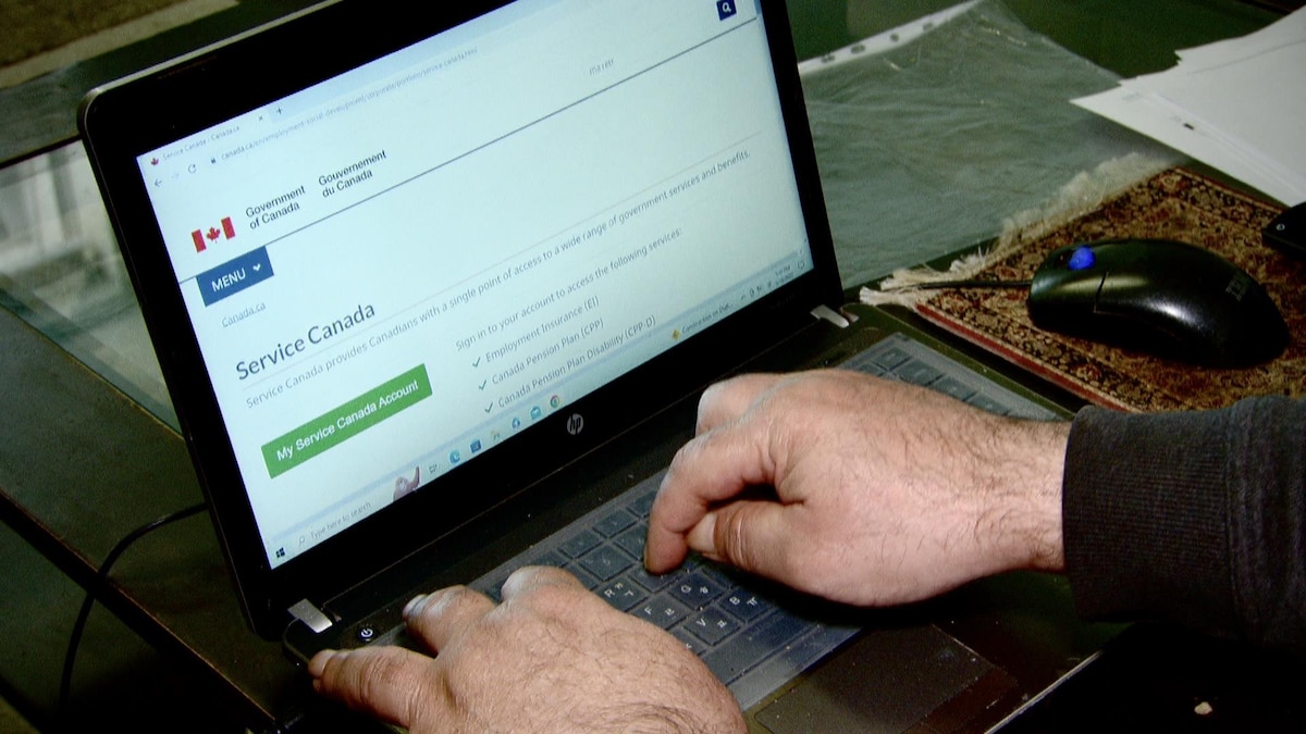 Des mains sur un clavier avec le site web de Service Canada à l'écran.