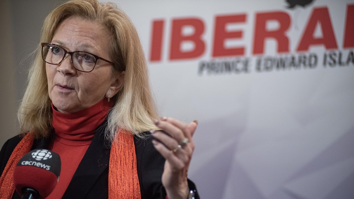 Sharon Cameron parle au micro devant un grand écran sur lequel le mot « Liberal » apparaît. 