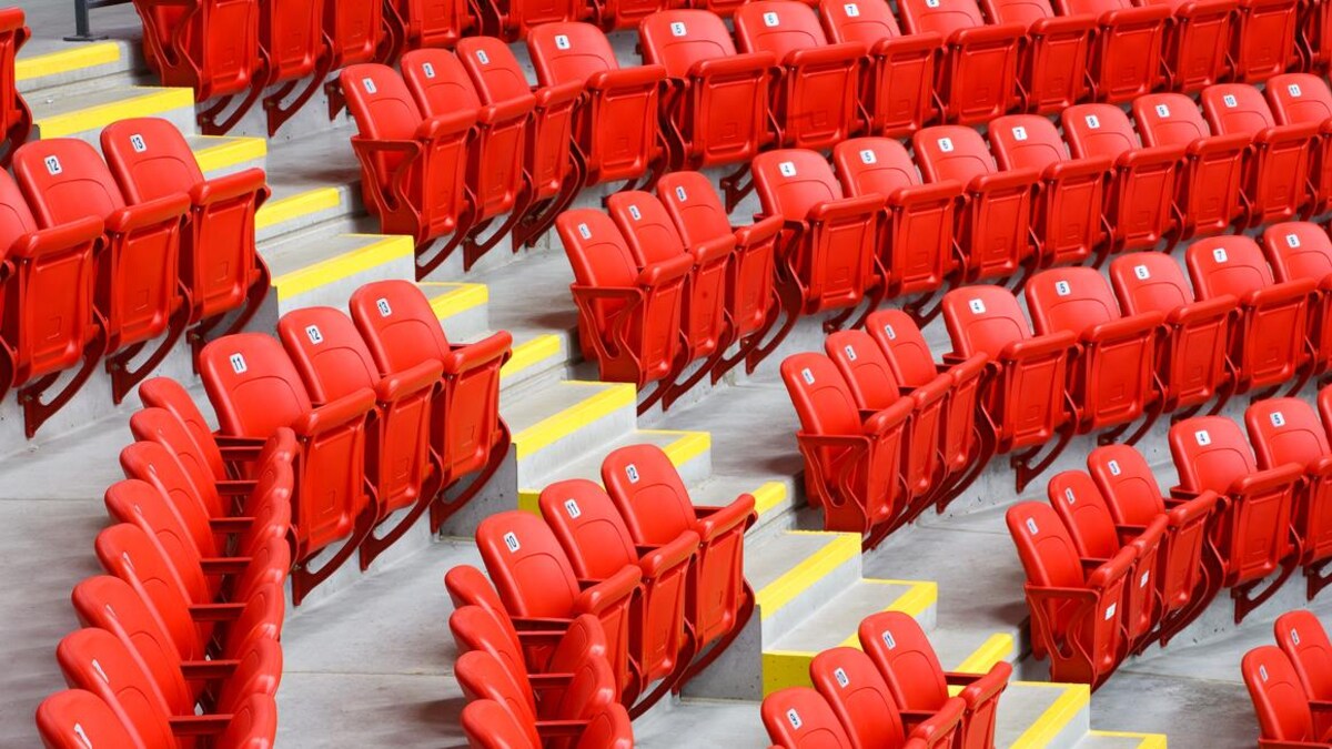 Des rangées de sièges rouges dans un stade séparées par une allée.