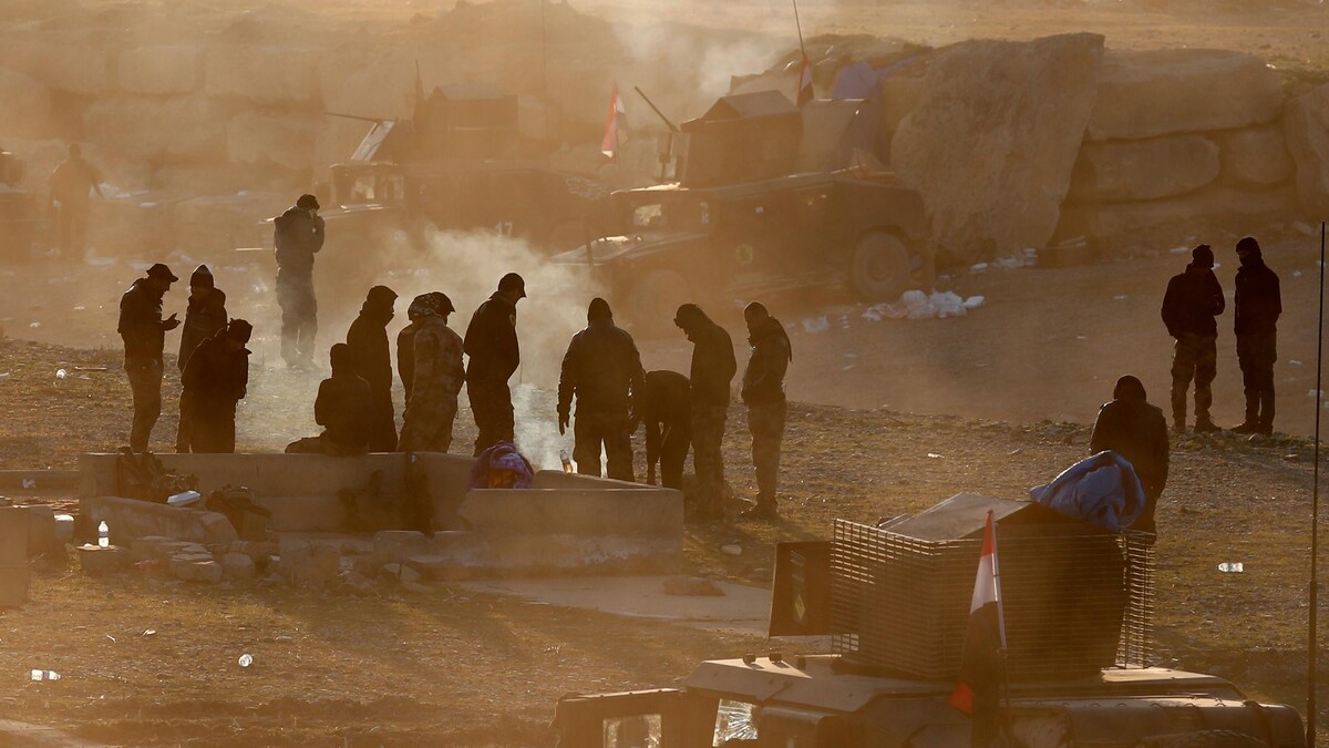 Les soldats des Forces spéciales iraquiennes se tiennent autour d'un feu dans leur camp situé à l’extérieur de Mossoul. 
